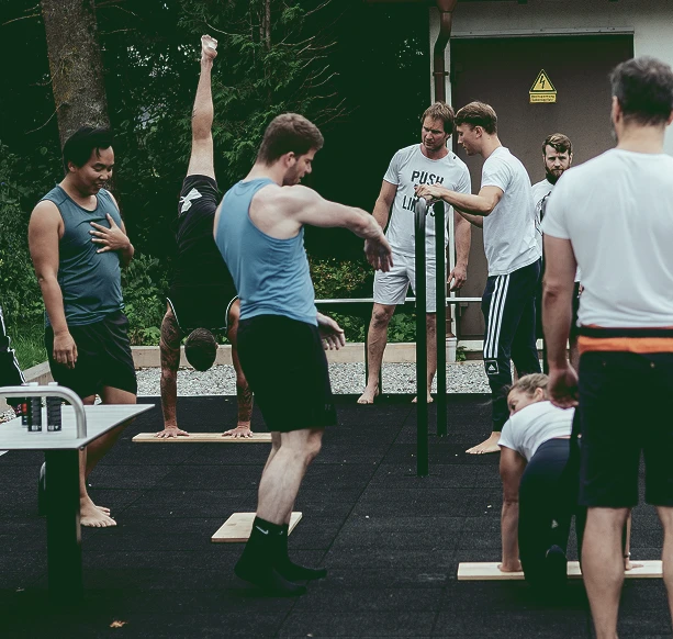 Outdoor-Training an Barren: Teilnehmende üben Handstand, Mobilität und Technik unter Anleitung.